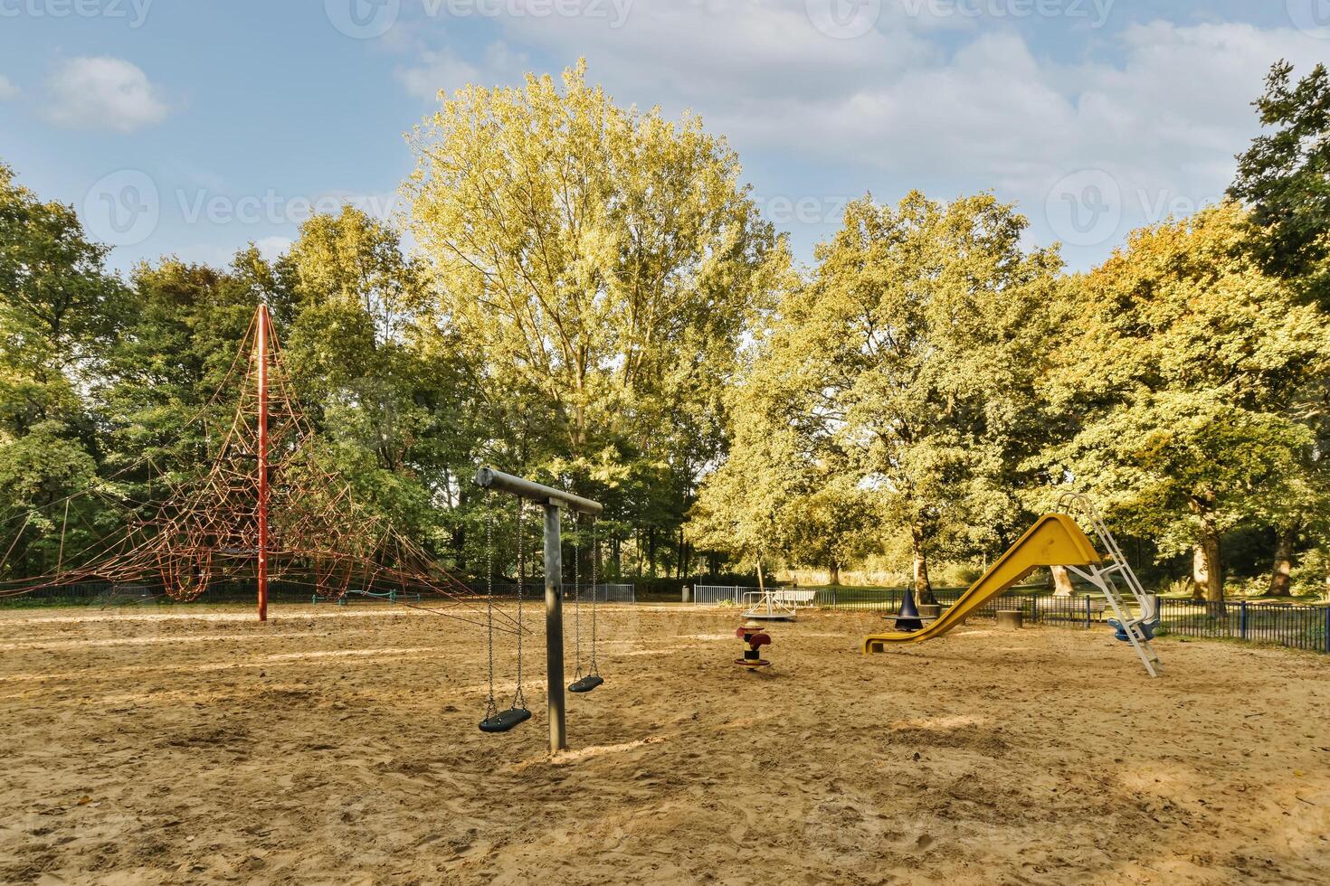 A playground with swings and a slide in the middle of a park photo