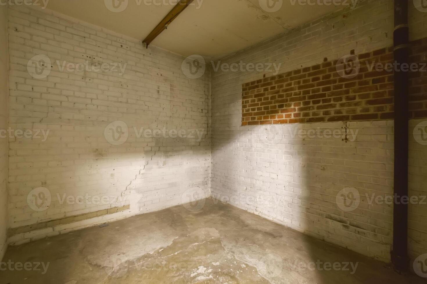 An empty room with a brick wall and a pipe photo