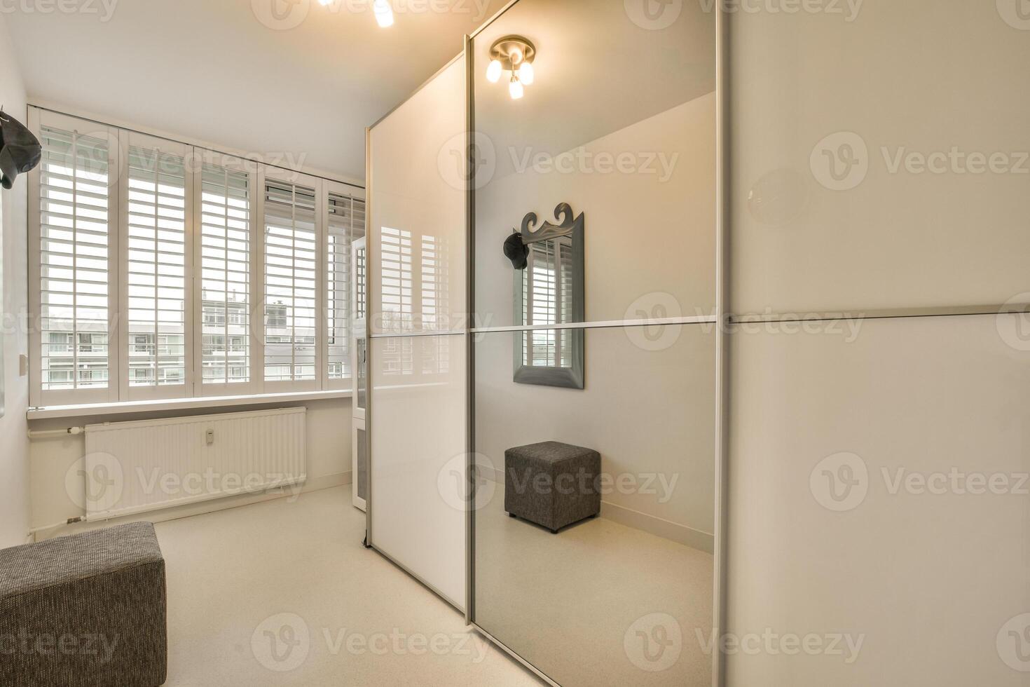 A white room with a mirror and a bench photo