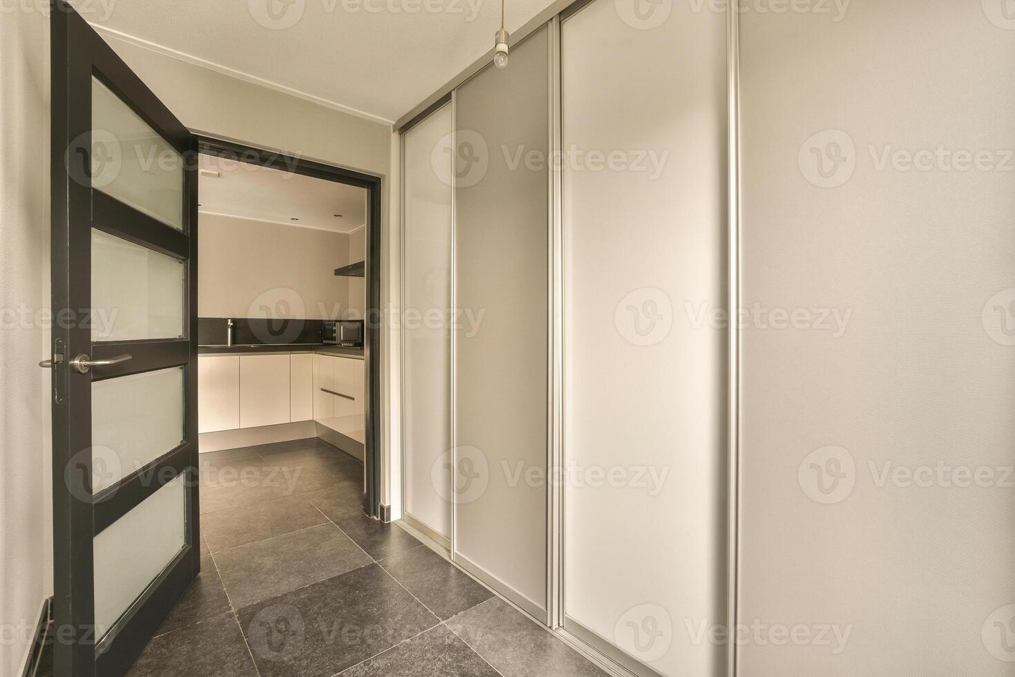 A hallway with a door and a kitchen photo