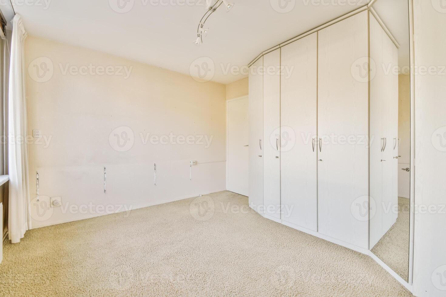 A room with white cabinets and a mirror photo