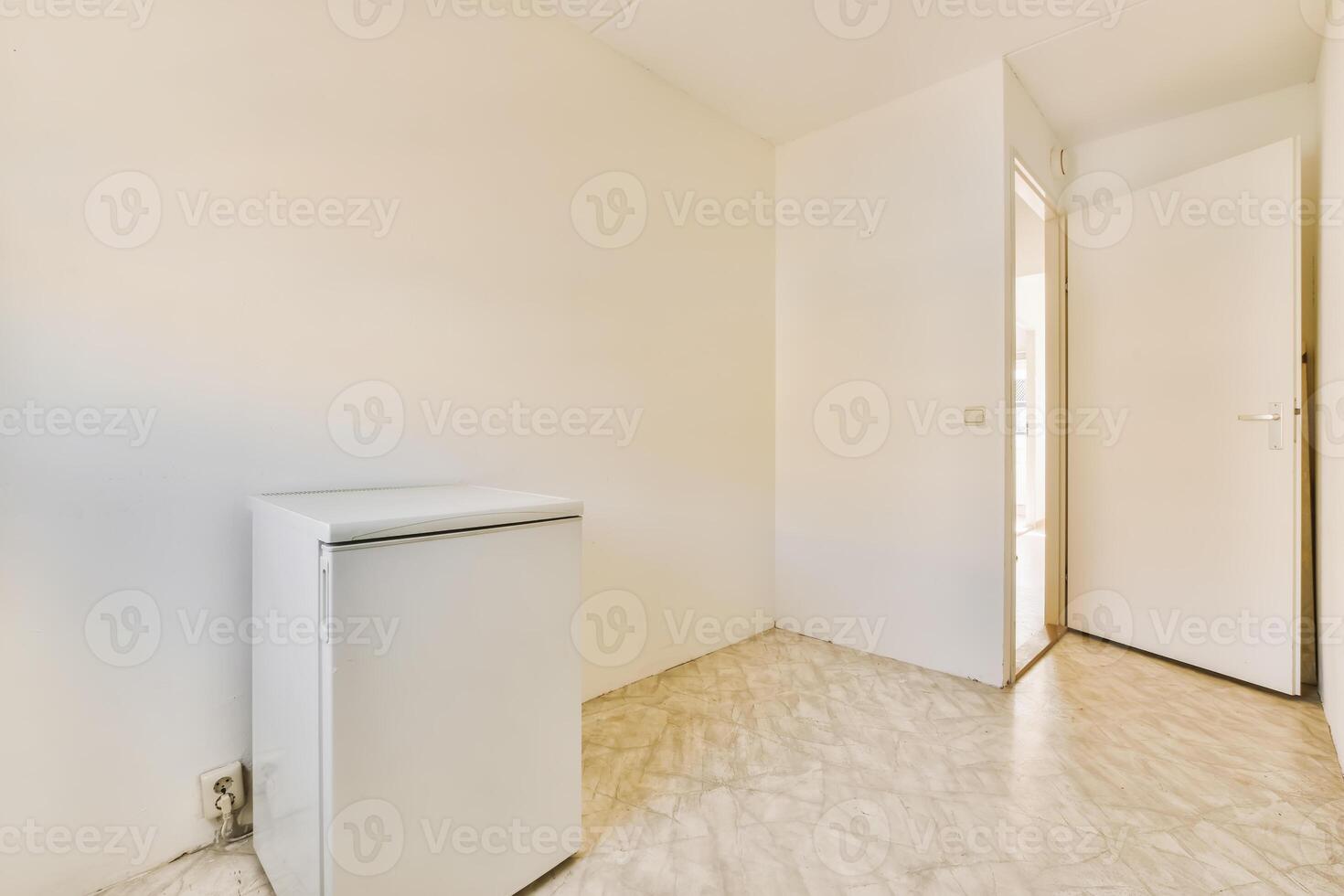 A white refrigerator in a small room with a door photo