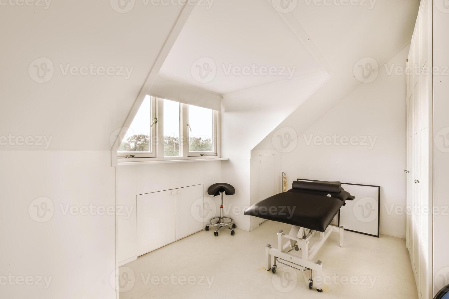 A white room with a black chair and a window photo