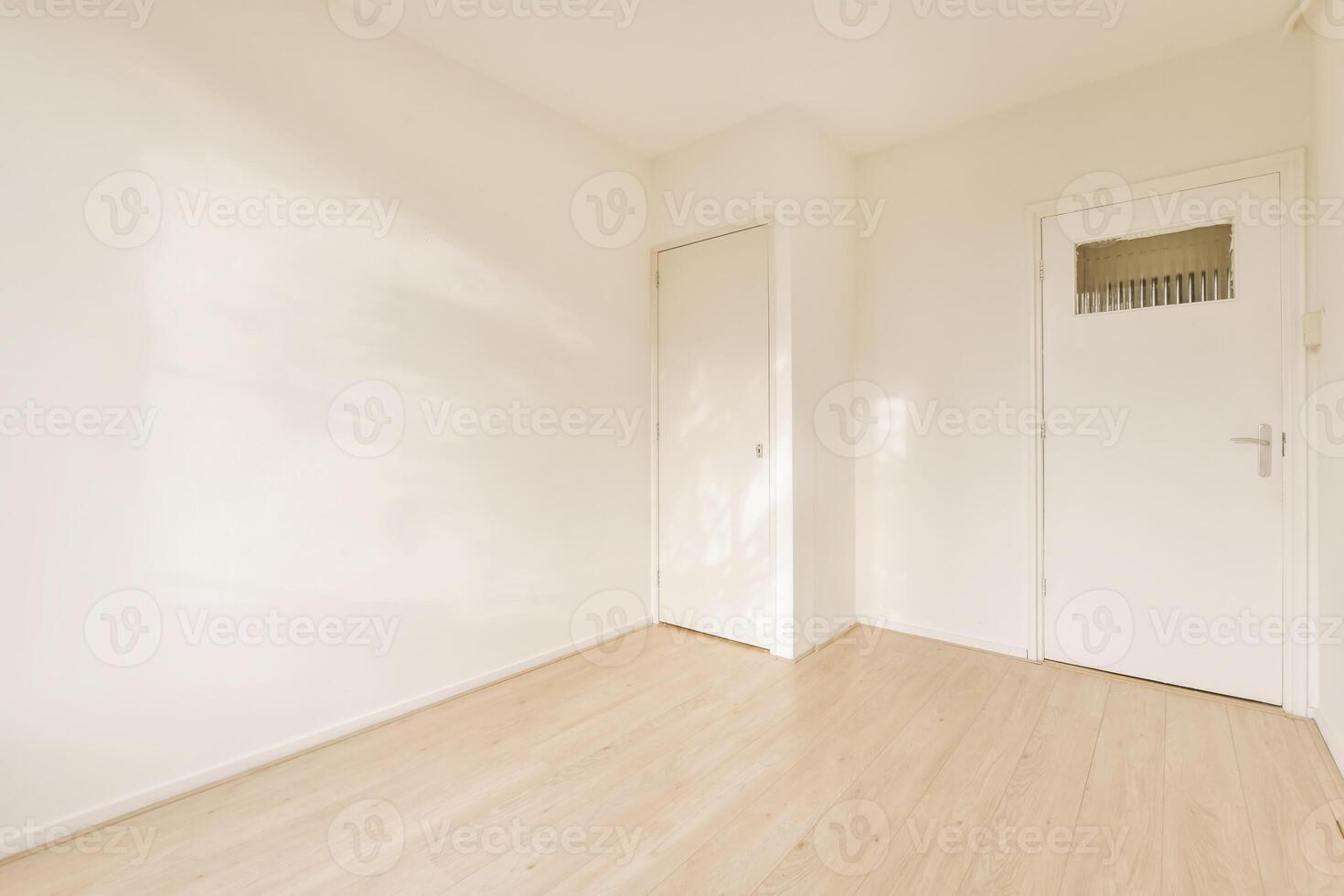 An empty room with a wooden floor and white walls photo