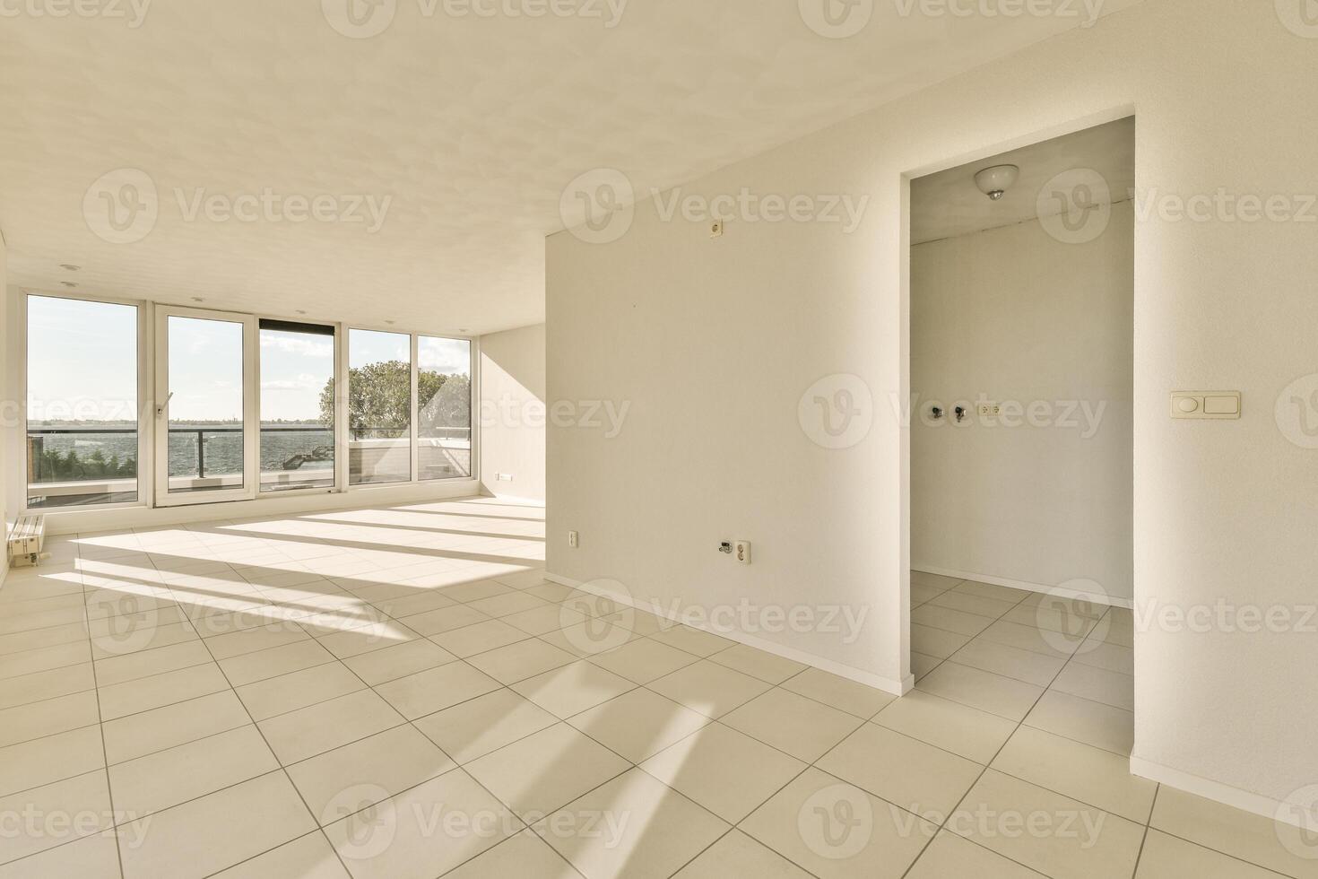 An empty room with white tile floors and large windows photo