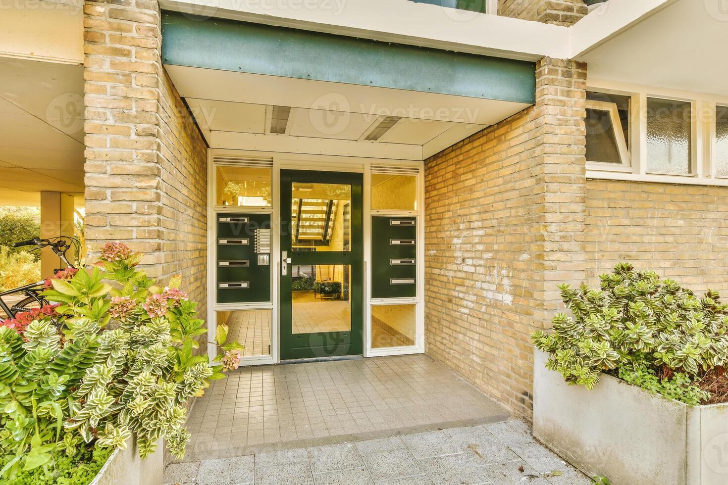 A brick building with green doors and green plants photo