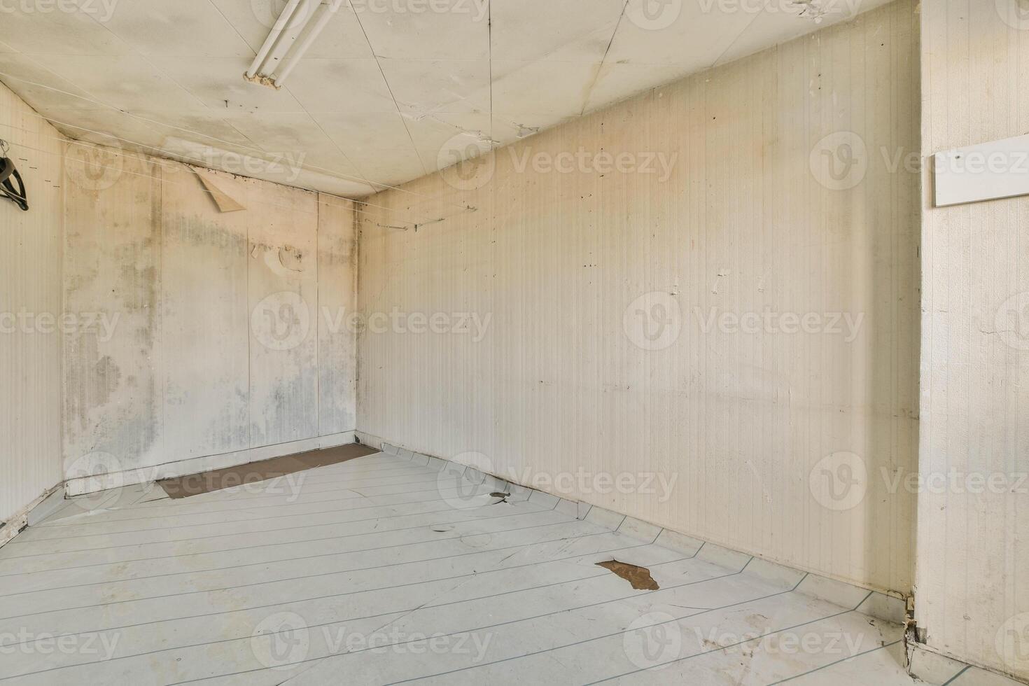 An empty room with a white floor and peeling paint photo