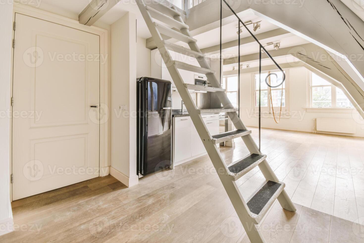 An open loft with stairs and a refrigerator photo