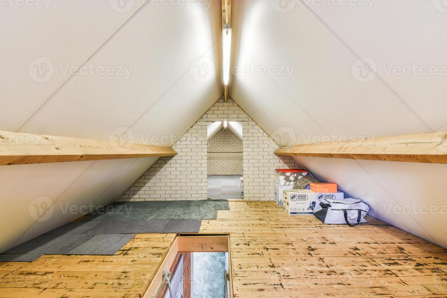 A small attic with a wooden floor and a ladder photo