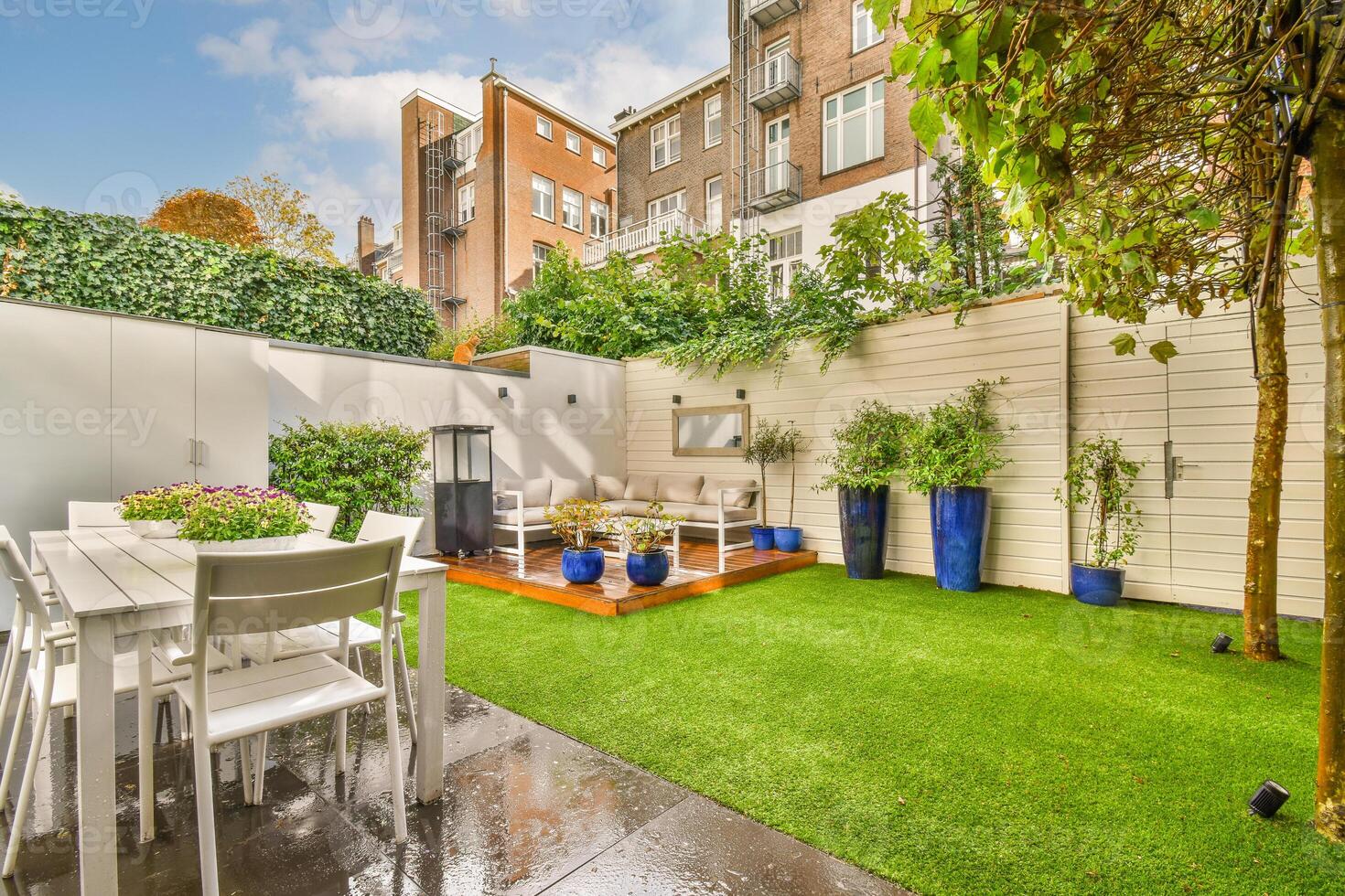 A backyard with a table and chairs, a lawn and artificial grass photo