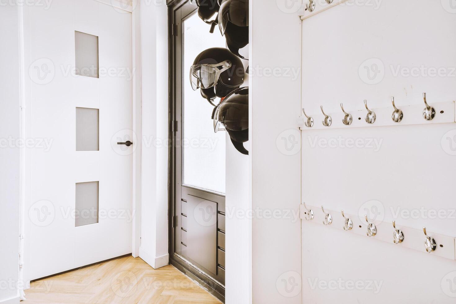 A hallway with a door and a wall with a bunch of helmets photo