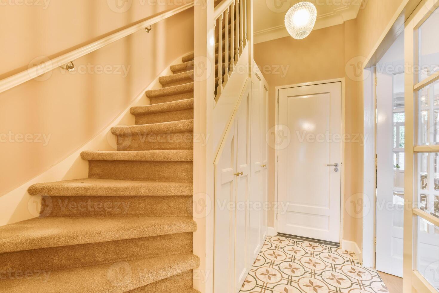 A hallway with a staircase and a door photo