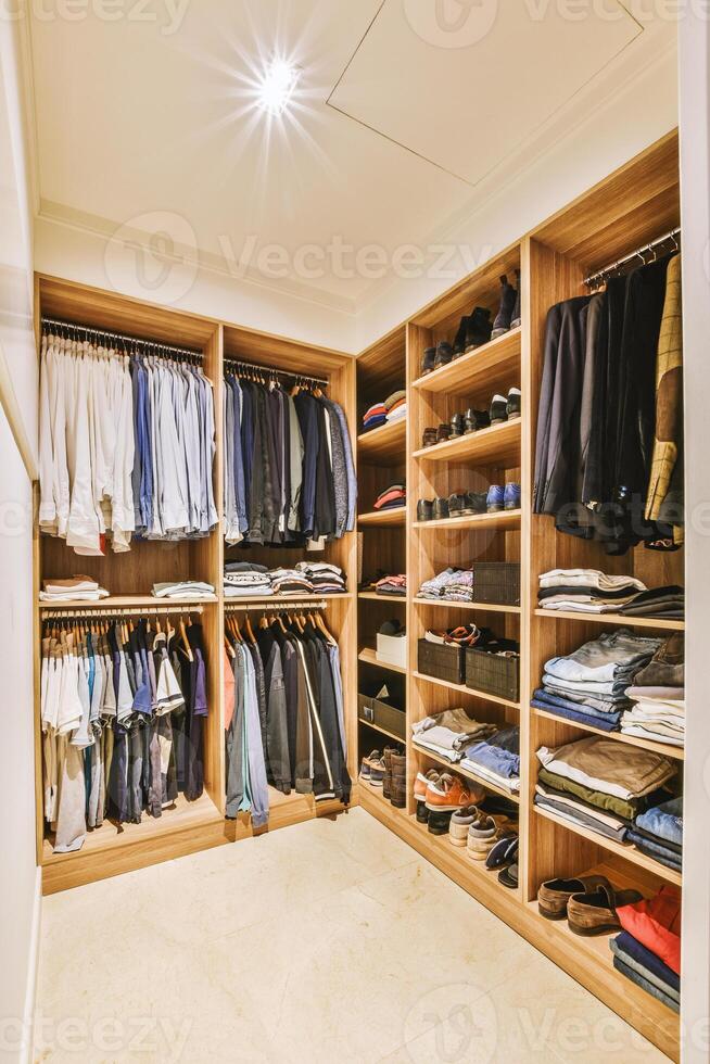 A walk in closet with clothes and shoes photo