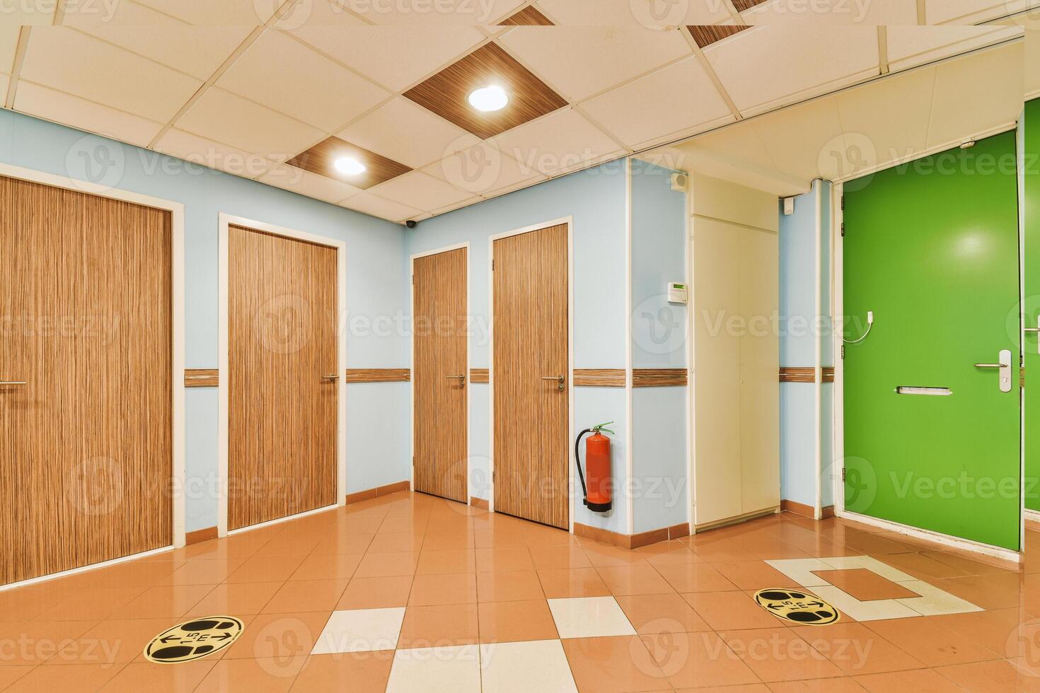 A hallway with green doors and brown tile floor photo