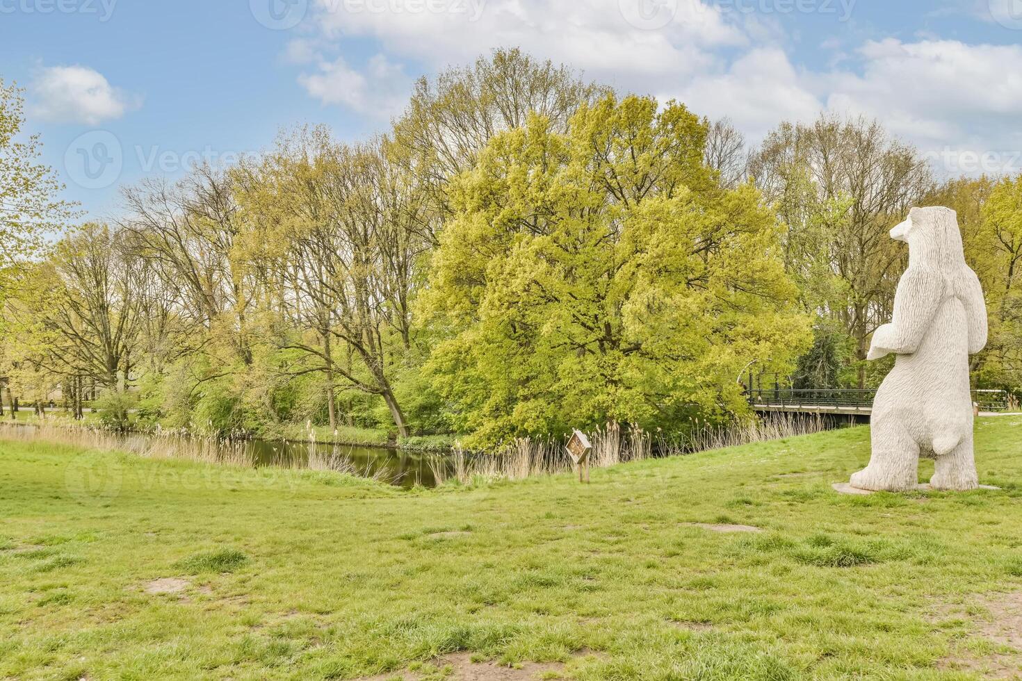 A white bear statue in a field near a river photo