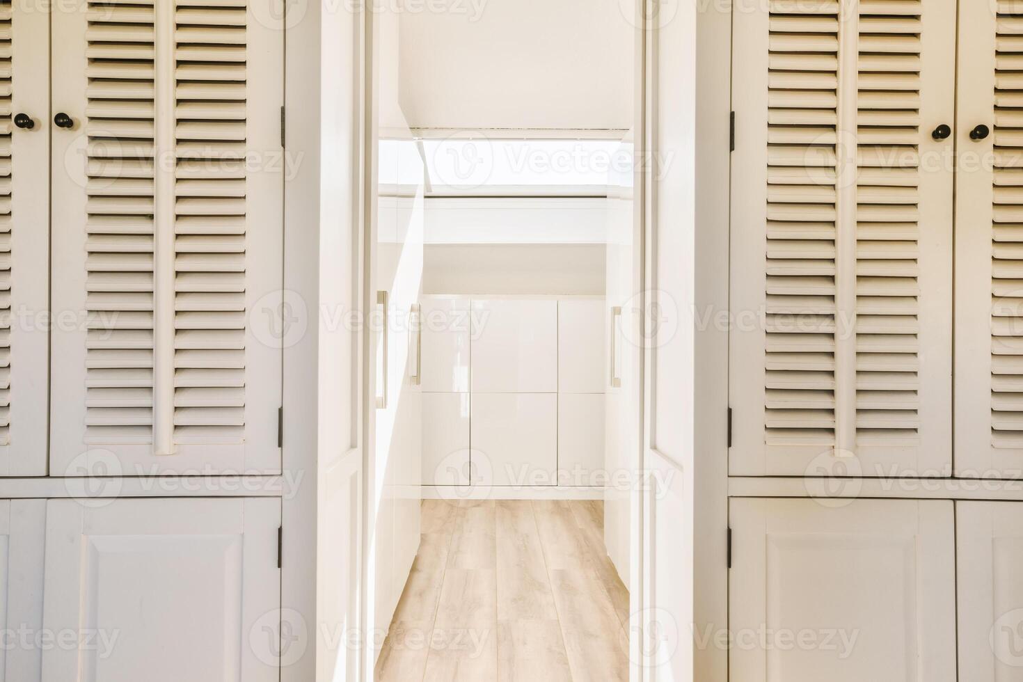 A hallway with white cabinets and wooden floors photo