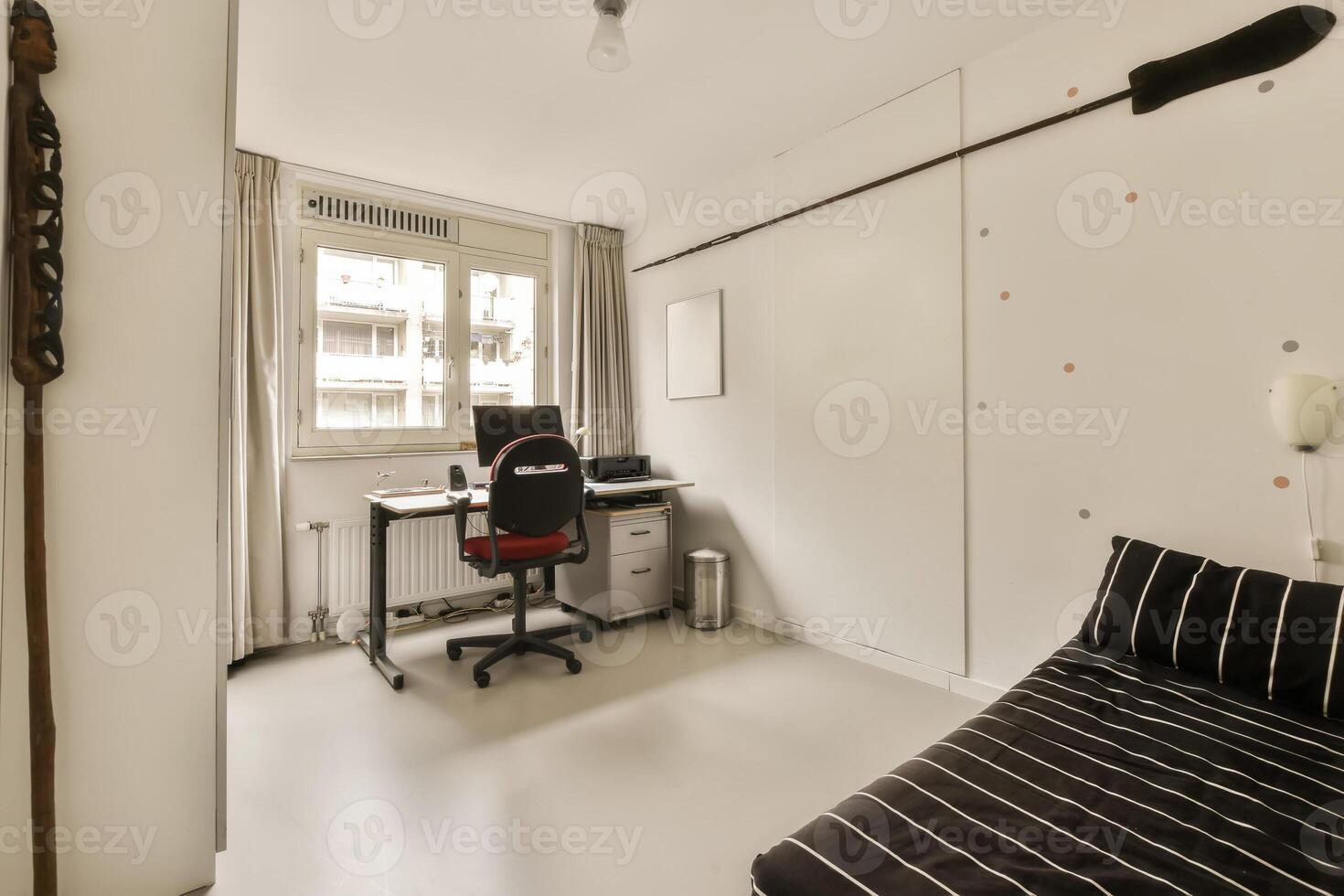 A small room with a desk, chair and a computer photo