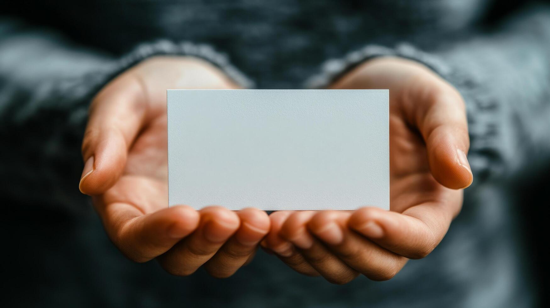 Person holding a blank business card in hands with a soft background during daylight photo