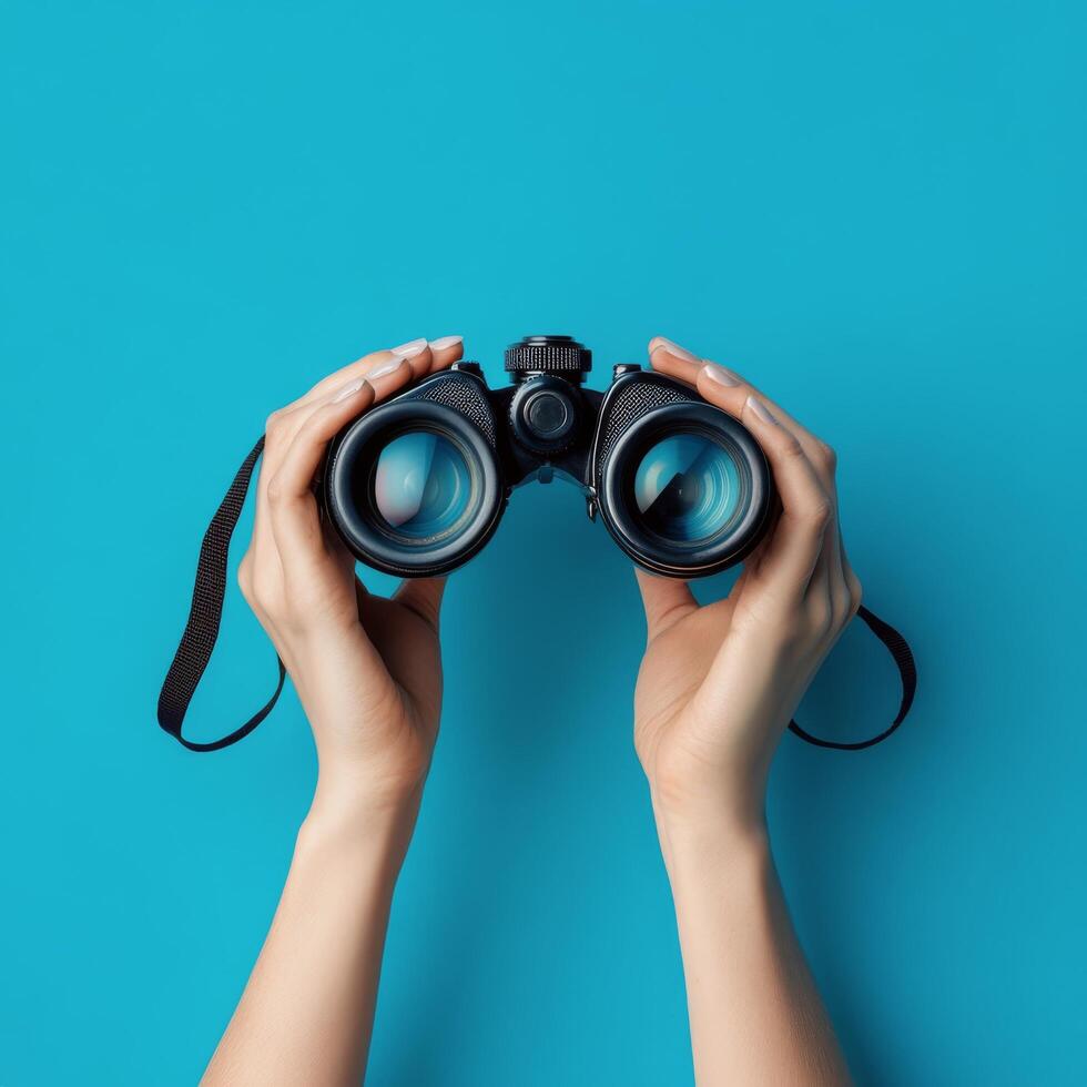 Hands holding binoculars against a vibrant blue background showcasing a sense of exploration photo