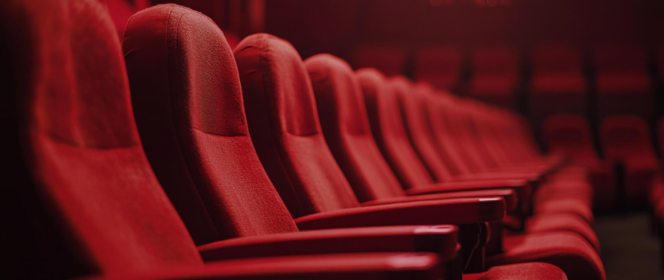 Empty red theater seats await moviegoers in a dimly lit cinema setting photo