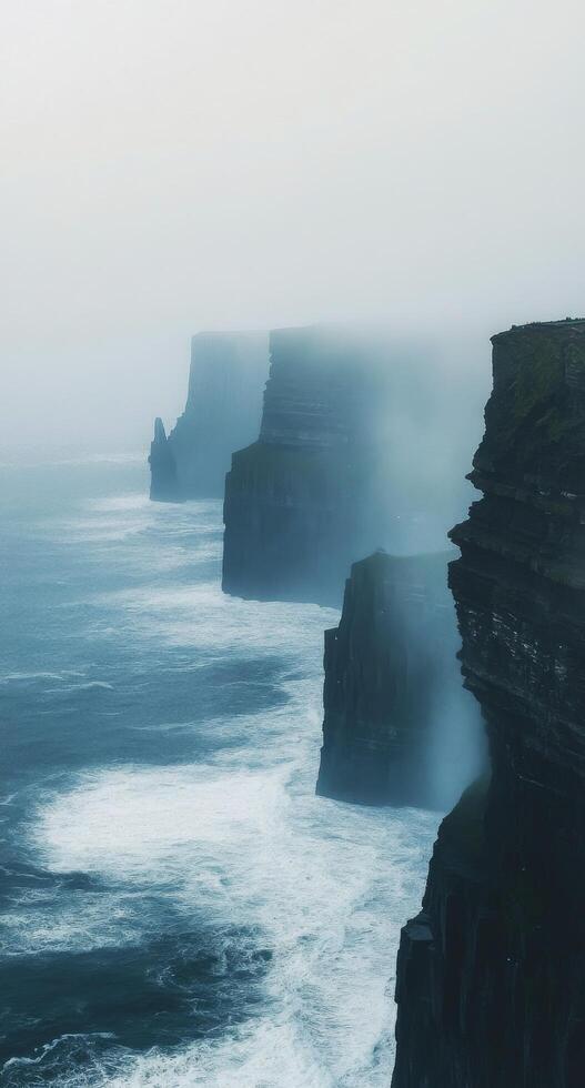 Misty cliffs and crashing waves along the rugged coast at Cliffs of Moher in Ireland photo