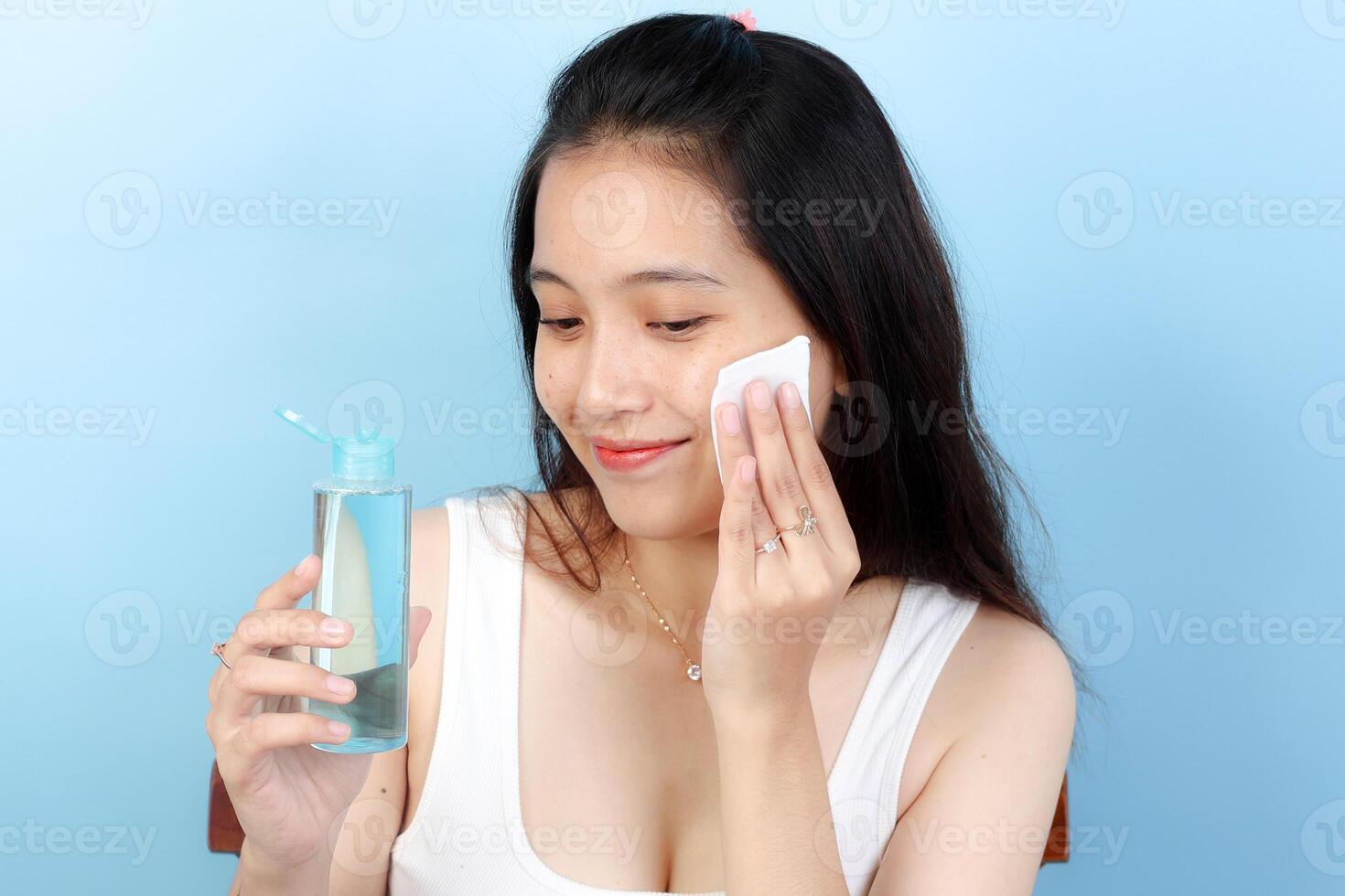 Asian Young Woman Tapping Her Face with Pad Using Micellar Water and for Makeup Removal photo
