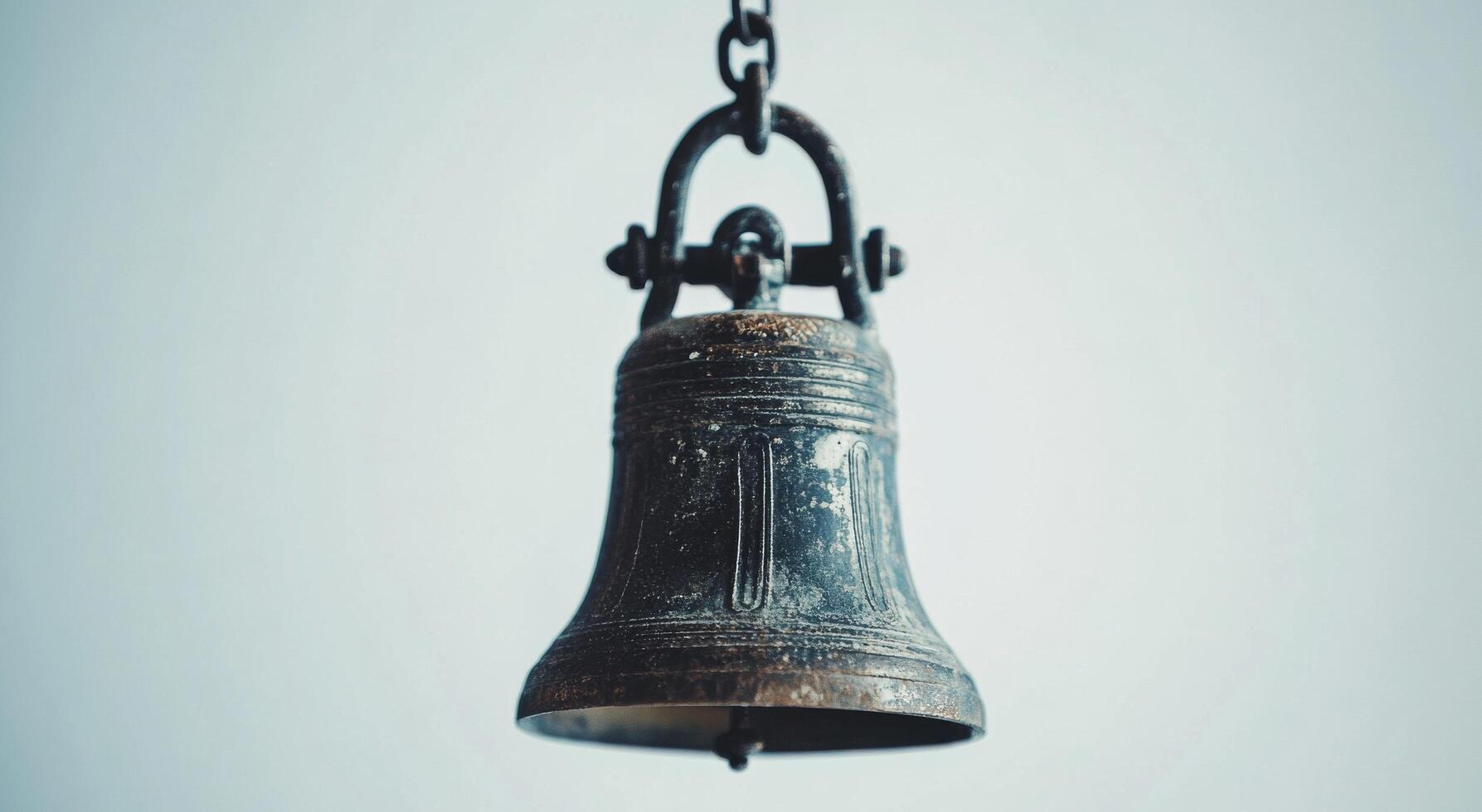 Rustic bronze bell hanging from a branch with blurred background of autumn leaves during daylight photo