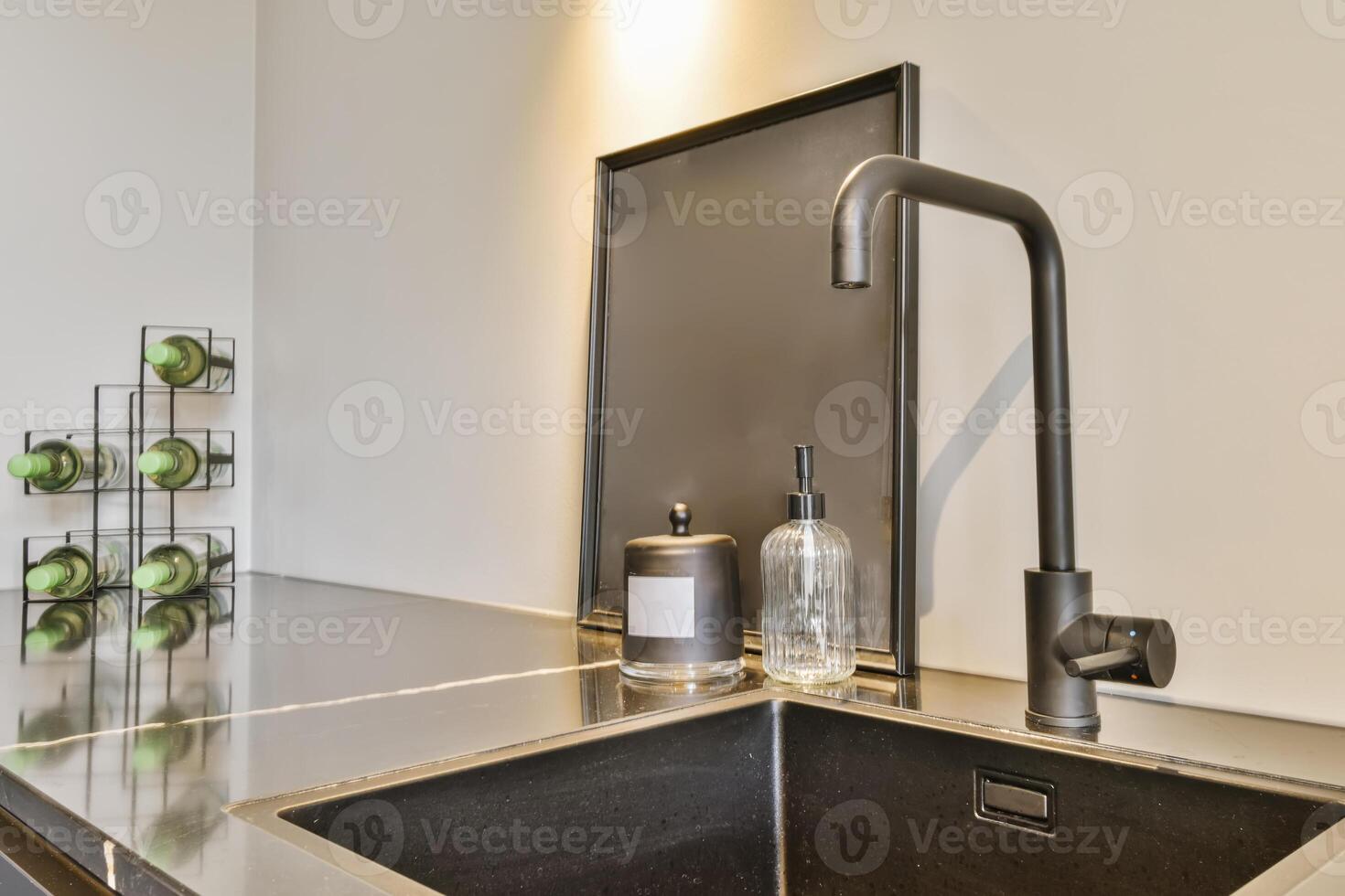 A kitchen sink with a black faucet and a mirror photo