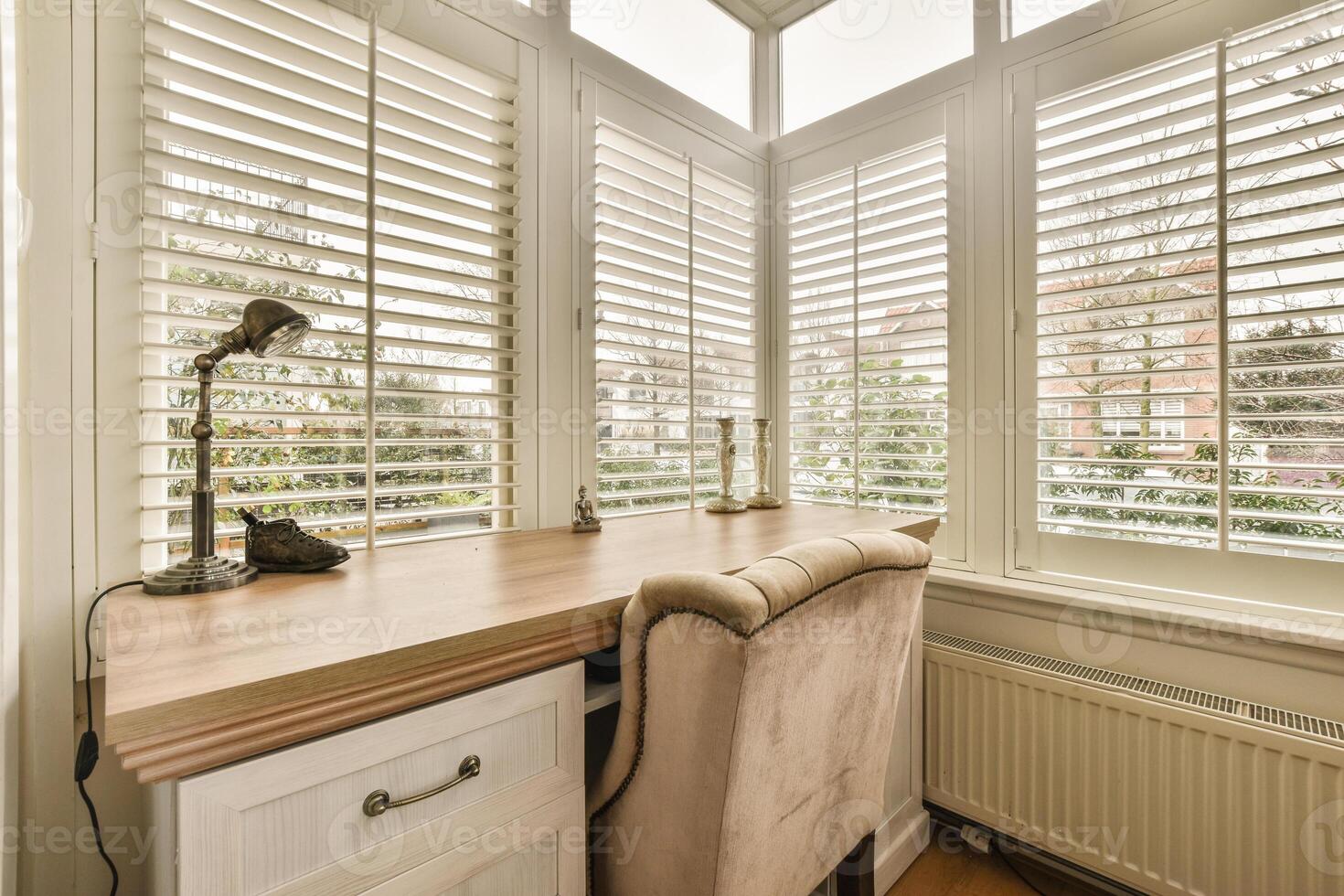 A desk with a chair in front of windows photo