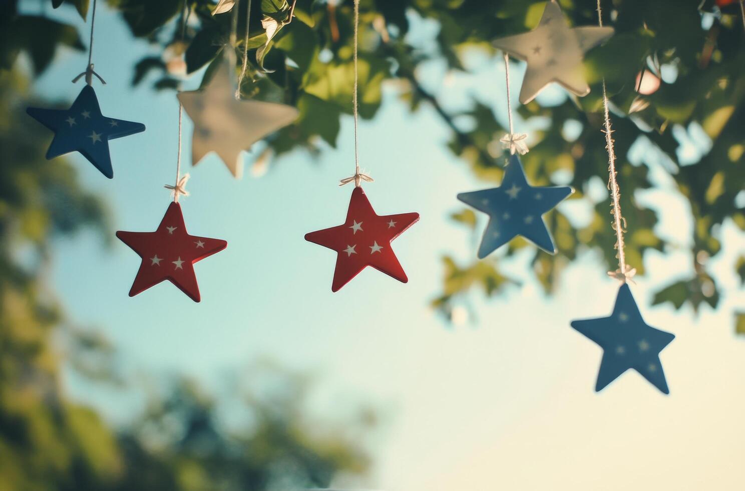 Colorful stars hanging against a clear sky while sunlight filters through the leaves photo