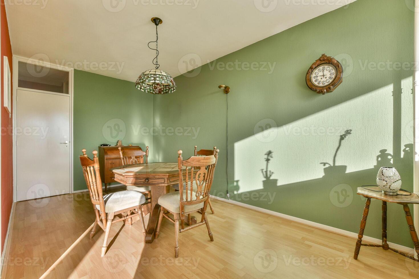 A dining room with a table and chairs in front of a green wall photo
