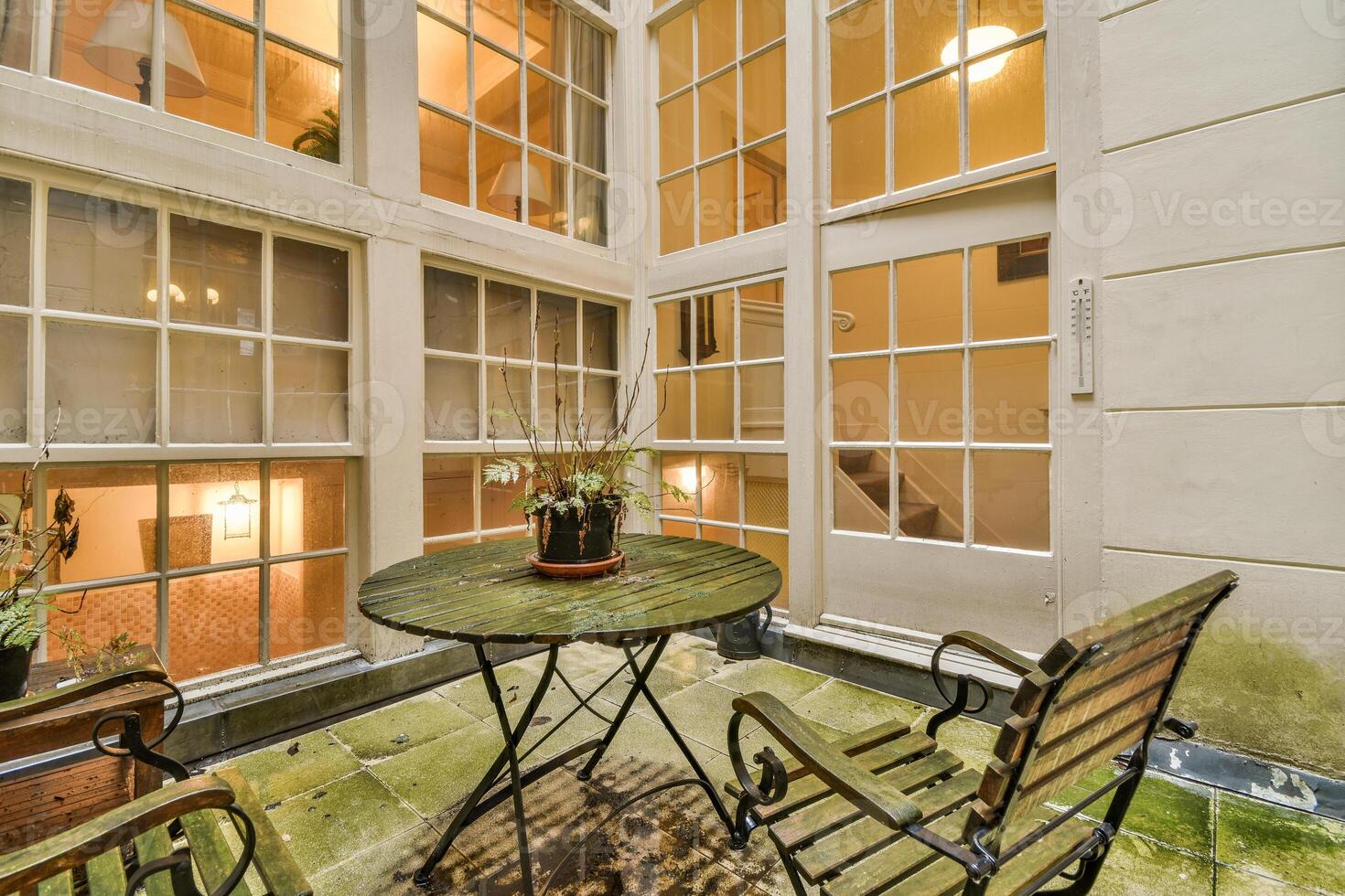 A patio with a table and chairs in front of a large window photo