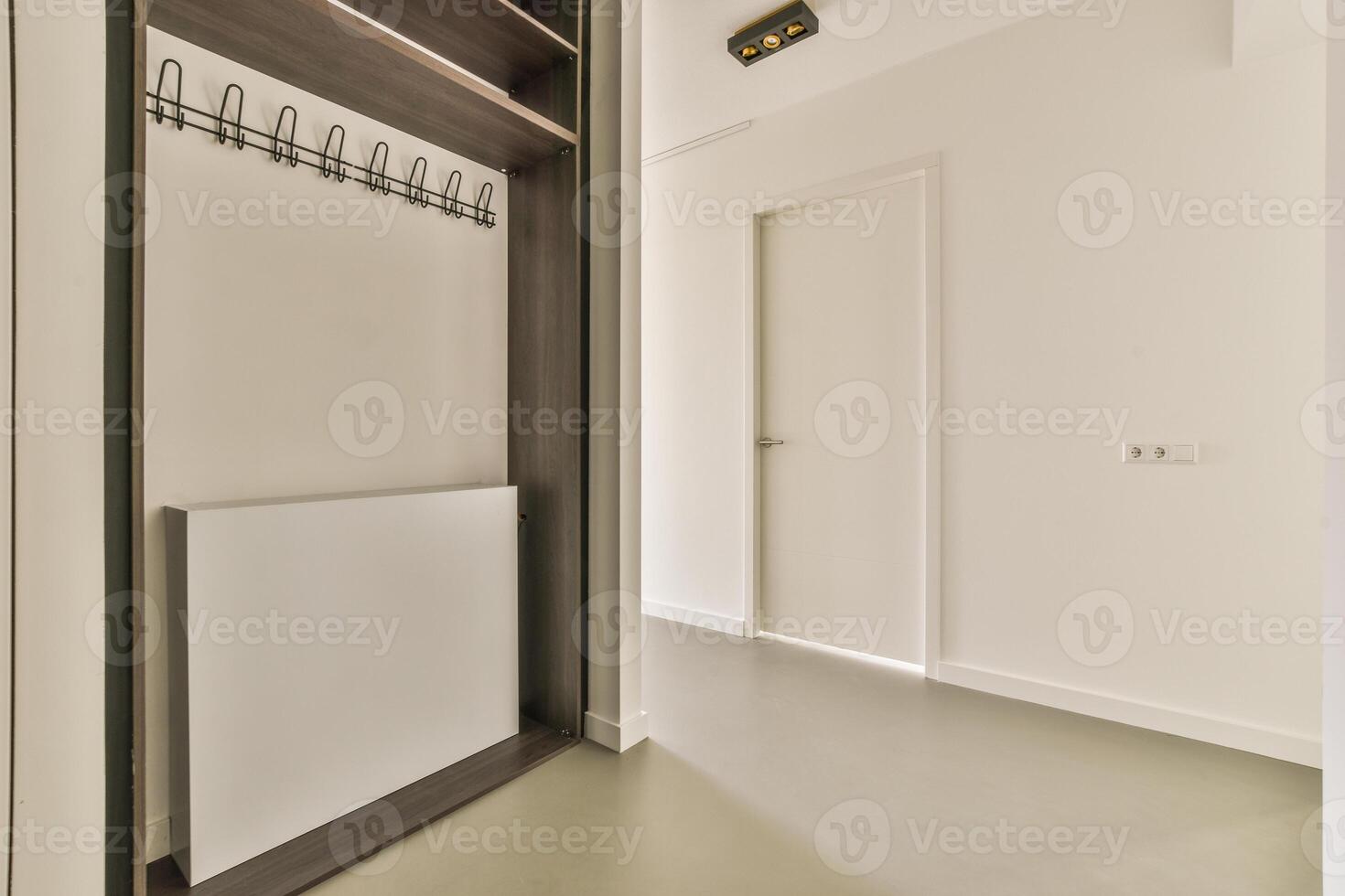 A white hallway with a coat rack and a door photo