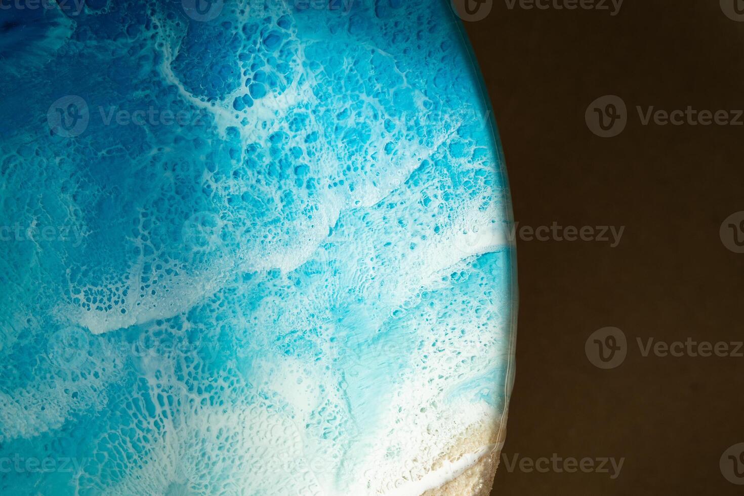 Closeup of epoxy resin painting with blue flowing, bubbly texture mirrors ocean waves, space, planet photo