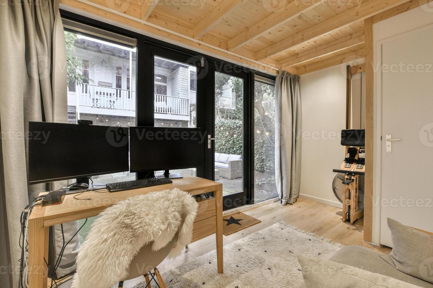 A small room with a desk, a computer and a window photo