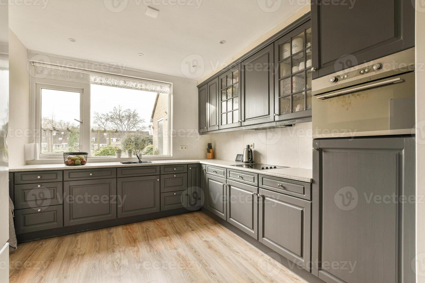 A kitchen with gray cabinets and a wooden floor photo