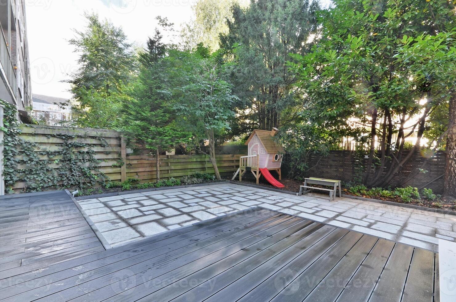 A backyard with a wooden deck and a swing set photo
