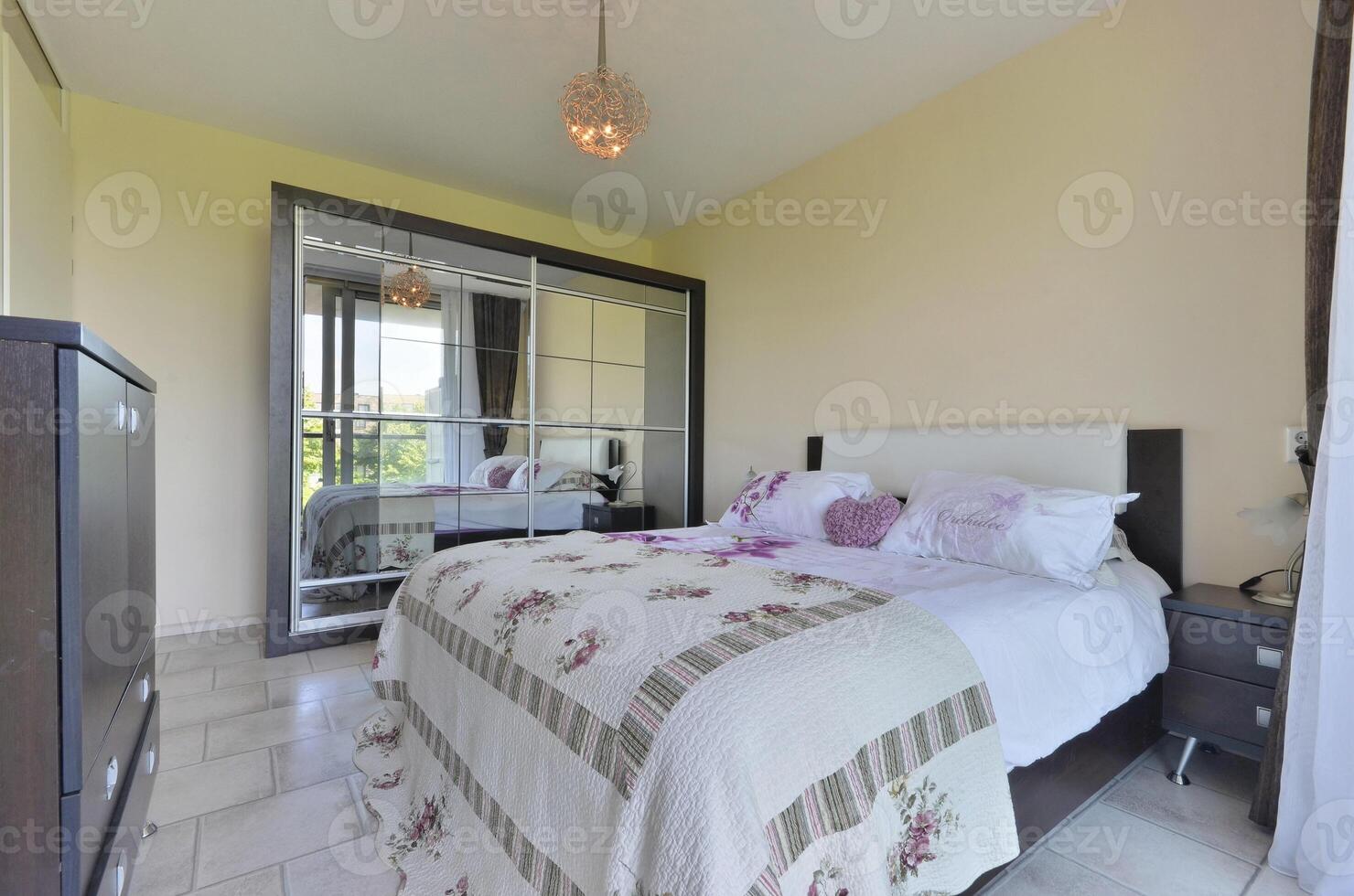A bedroom with a bed, dresser and mirror photo