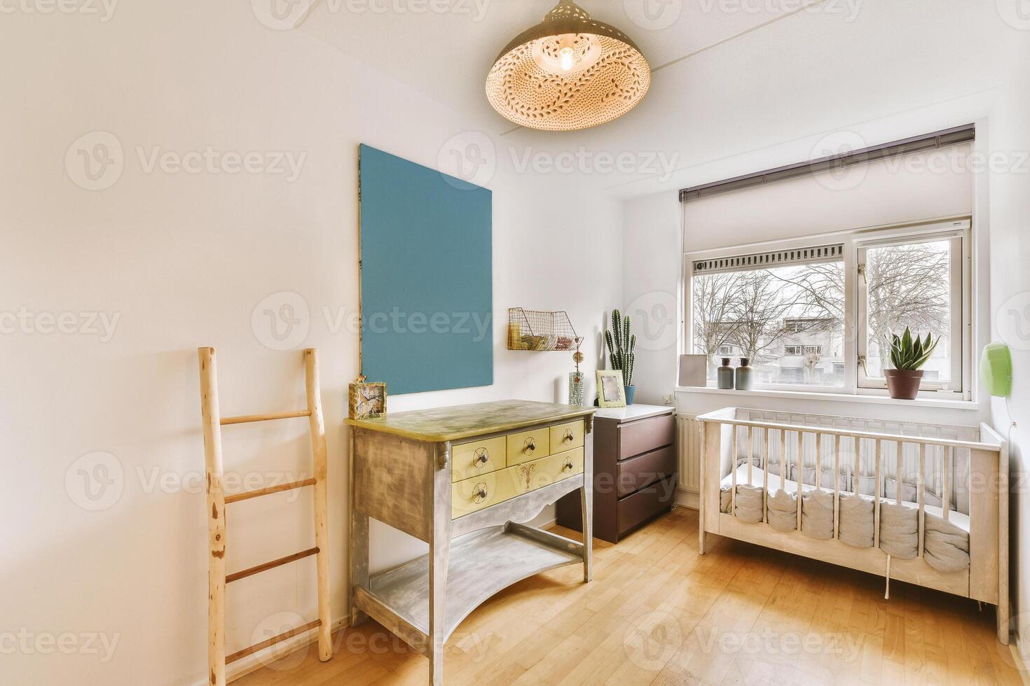 A small room with a crib, dresser and ladder photo