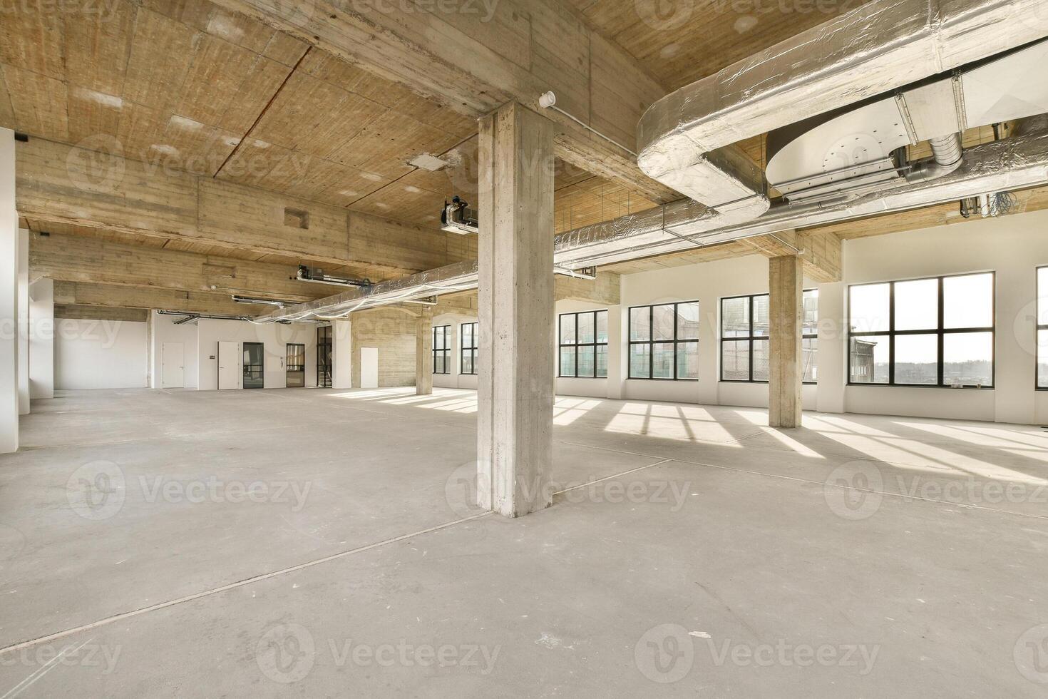 An empty office with large windows and concrete floors photo