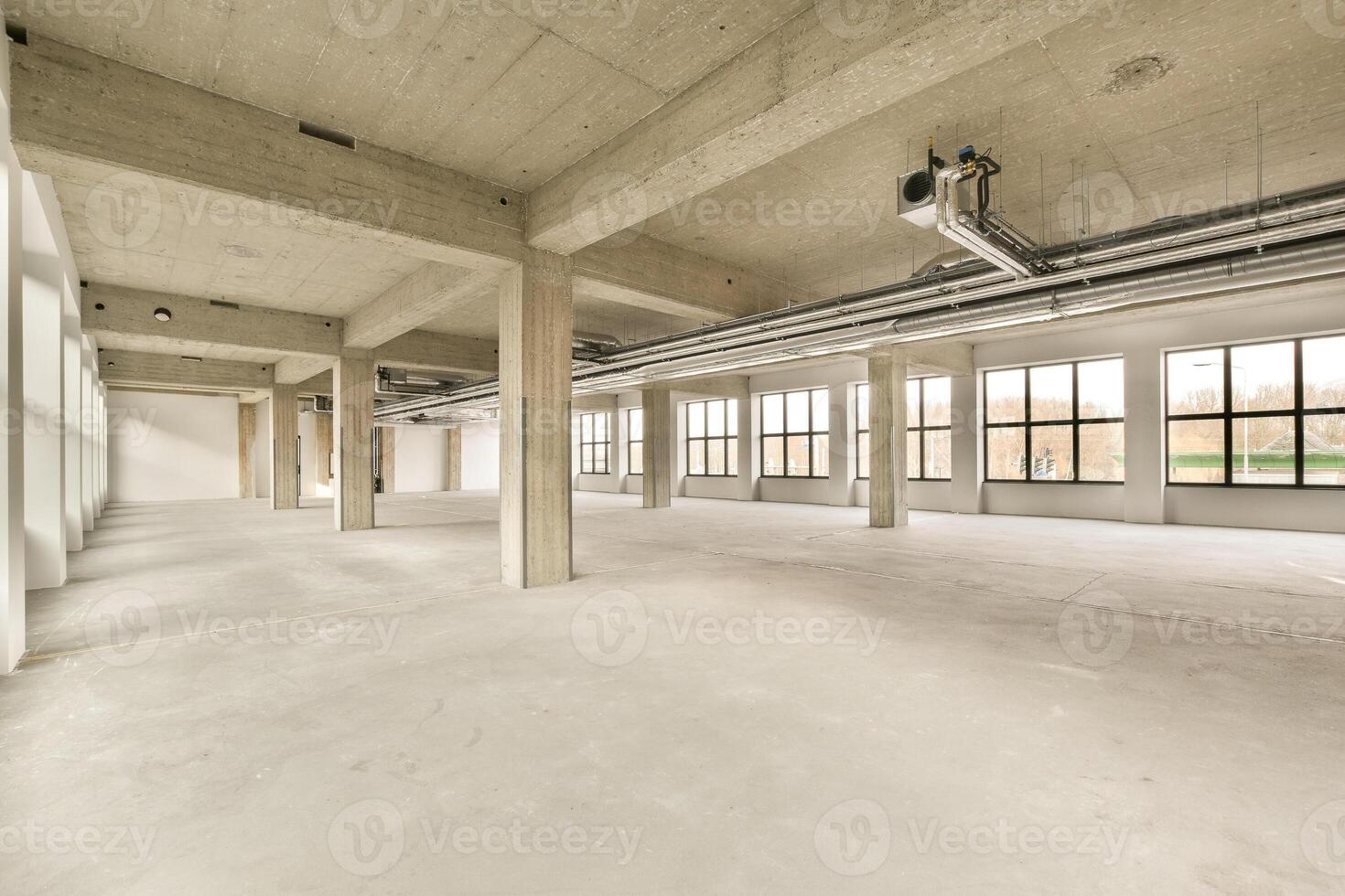 An empty office with large windows and concrete floors photo