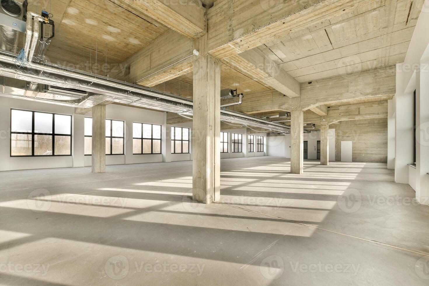An empty industrial space with large windows and concrete floors photo
