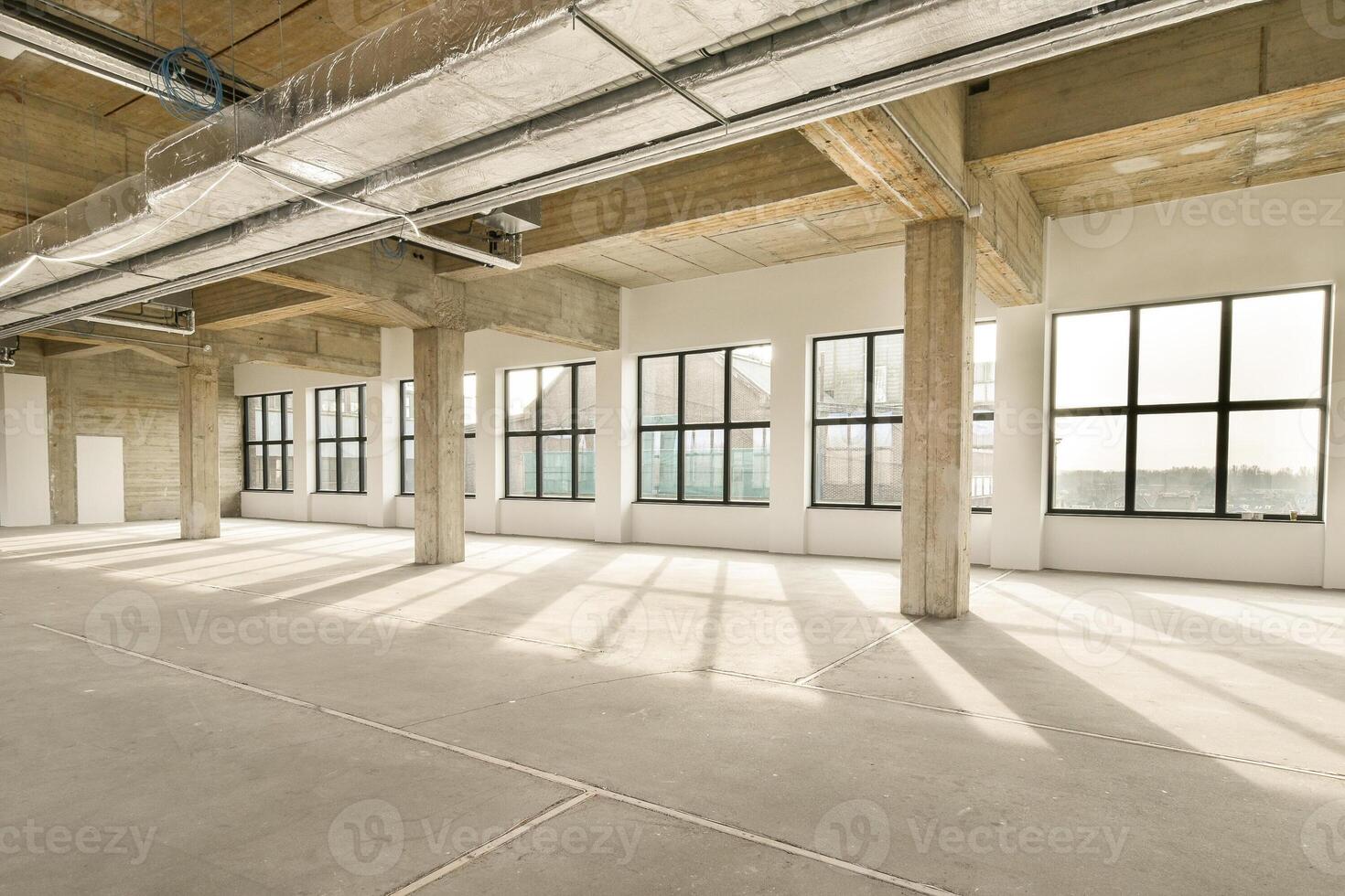 An empty warehouse with large windows and concrete floors photo