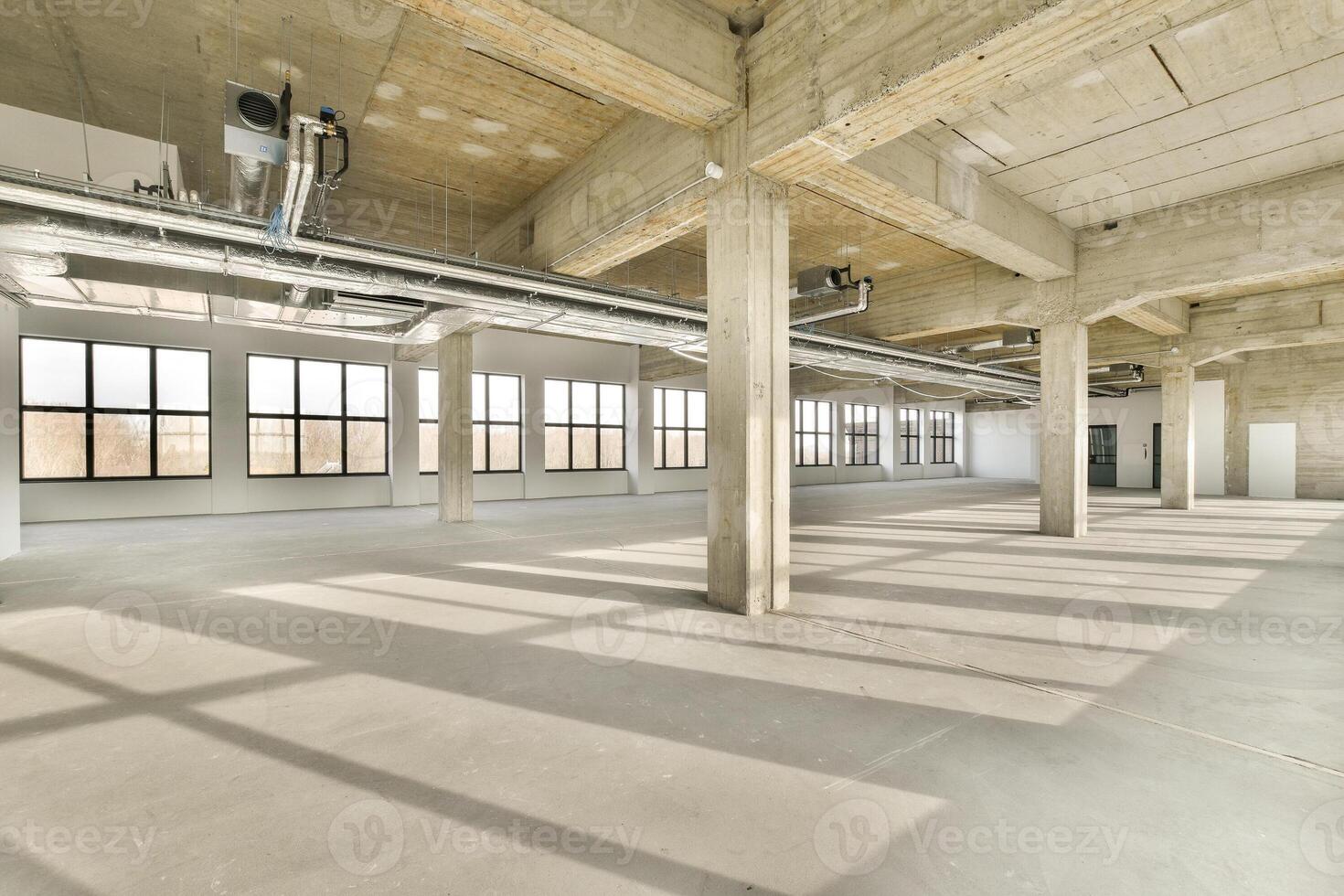 An empty warehouse with large windows and concrete floors photo