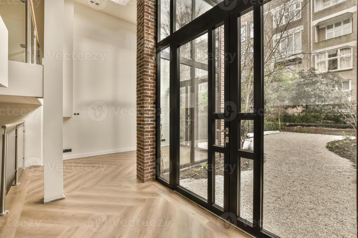 A large open area with a glass door and wooden floors photo