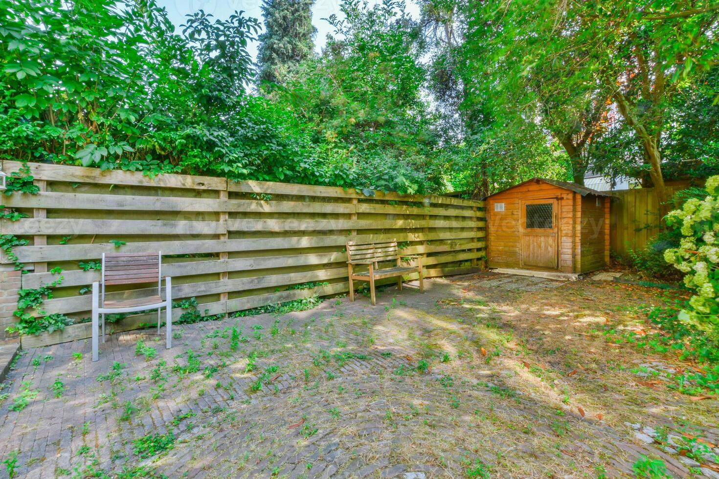 A backyard with a wooden fence and a bench photo