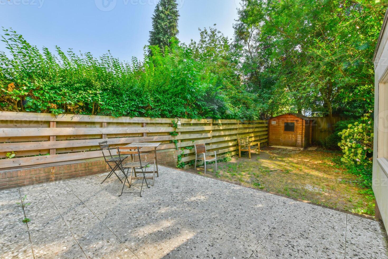 A backyard with a wooden fence and a patio photo