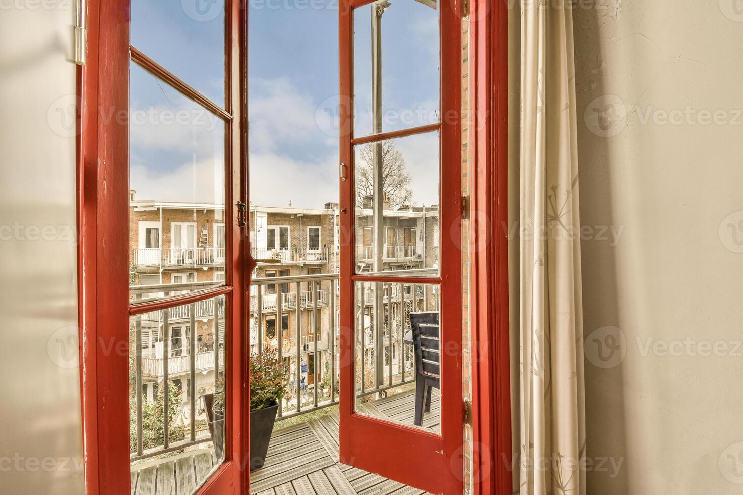 A red door opens to a balcony with a view of the city photo