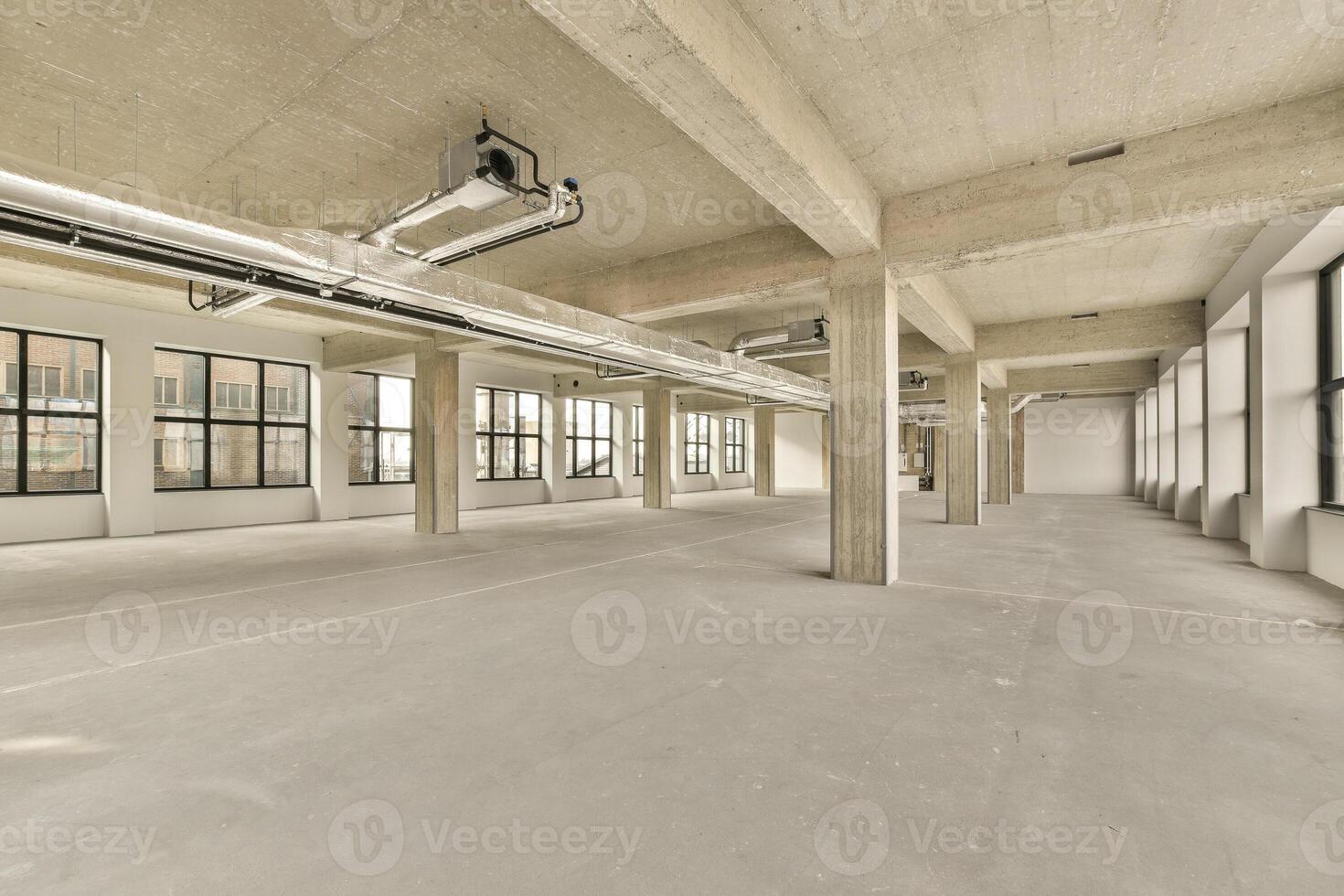 An empty office space with large windows and concrete floors photo