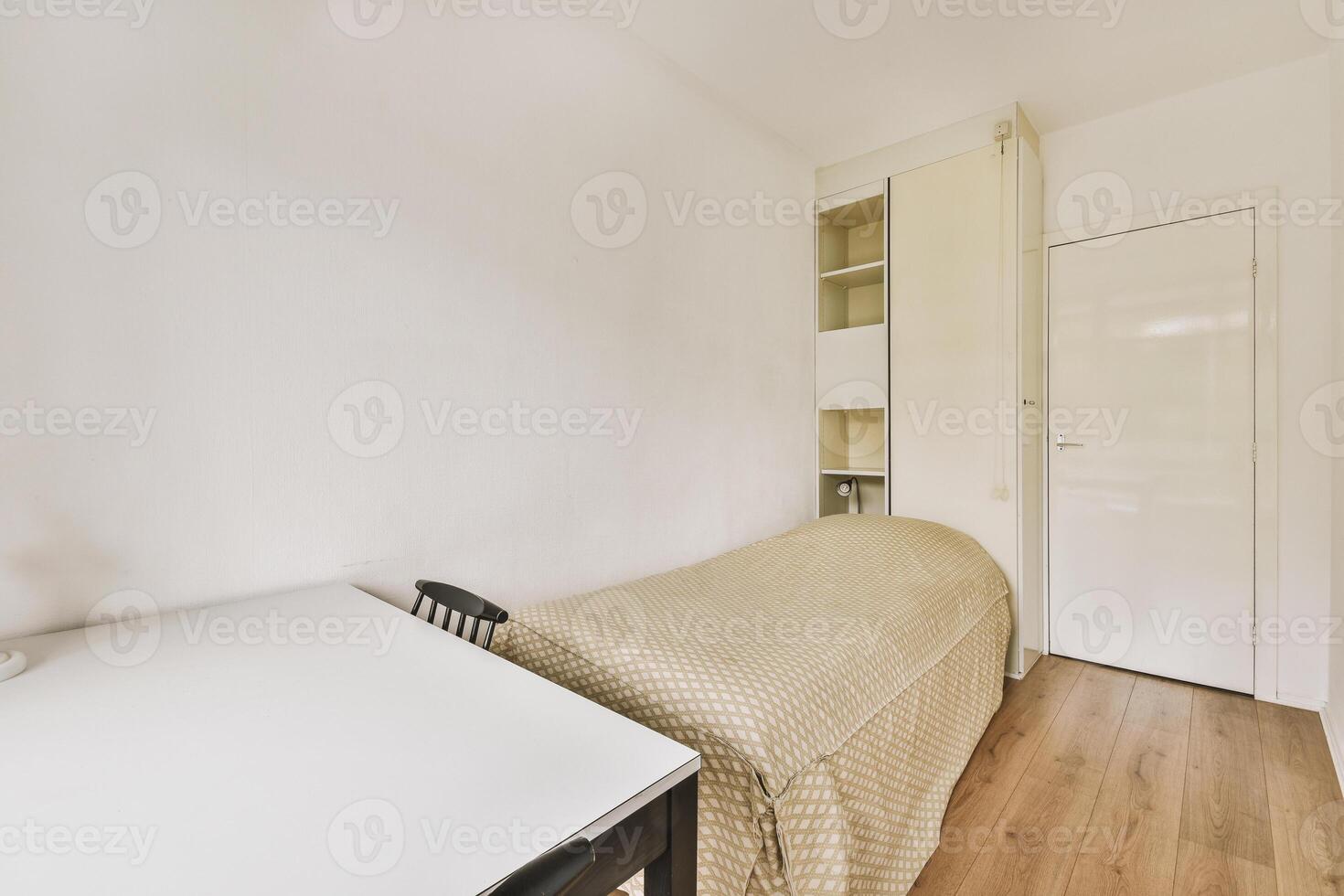 A small bedroom with a bed and desk photo